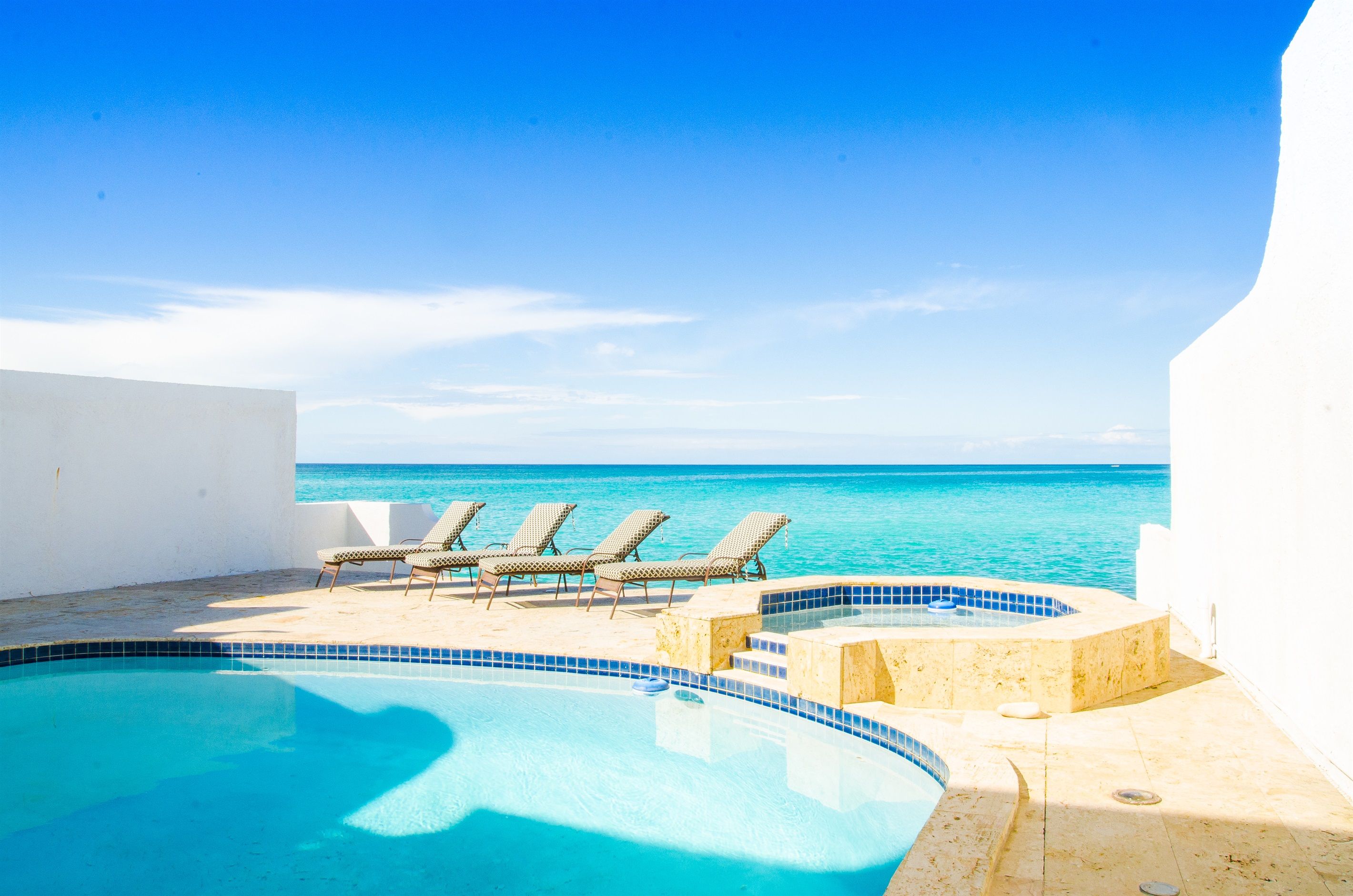 A pool with lounge chairs and a view of the ocean.