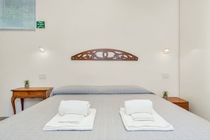 Ein Hotelzimmer mit einem Bett, zwei Nachttischen, einer Wanddekoration und einem Schild, das anweist, etwas zu öffnen.