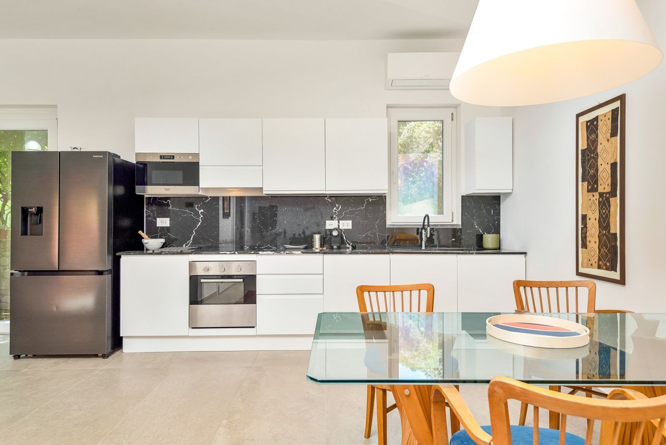 Une cuisine moderne avec des meubles blancs, des appareils en acier inoxydable et une table à manger en verre.