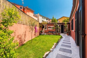 A courtyard with a paved path, a small lawn, and a building with a red facade. - [IndependentHouse] 5TERRE/ garden+parking+ A/C (La Spezia)