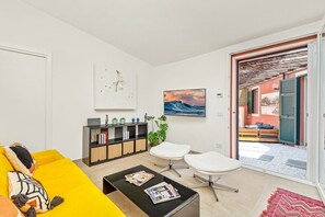 A modern living room with a yellow sofa, a black coffee table, and a white armchair. There is a bookshelf with various items and a painting on the wall. - [IndependentHouse] 5TERRE/ garden+parking+ A/C (La Spezia)