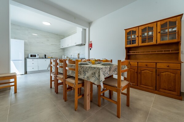 A dining area with a table set for four, wooden chairs, and a cabinet with glass doors.