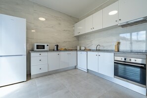 A modern kitchen with white cabinets, a built-in microwave, a dishwasher, and a stainless steel oven.