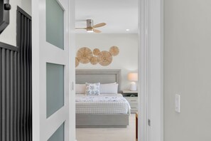 Ein Schlafzimmer mit einem Bett, einem Nachttisch, einer Lampe und einem Deckenventilator.