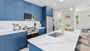 A modern kitchen with blue cabinets, a stainless steel stove, and a marble countertop. - Brand new, walking distance to Sombrero Beach! 4 Bed/4.5 Bath outdoor kitchen. (Marathon)
