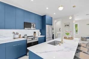 A modern kitchen with blue cabinets, a stainless steel stove, and a marble countertop. - Brand new, walking distance to Sombrero Beach! 4 Bed/4.5 Bath outdoor kitchen. (Marathon)