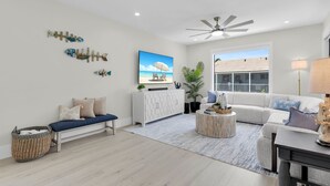 A modern living room with a sofa, a coffee table, a TV, and decorative wall art. - Brand new, walking distance to Sombrero Beach! 4 Bed/4.5 Bath outdoor kitchen. (Marathon)