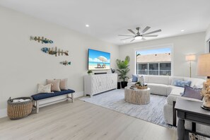 A modern living room with a sofa, a coffee table, a TV, and decorative wall art. - Brand new, walking distance to Sombrero Beach! 4 Bed/4.5 Bath outdoor kitchen. (Marathon)