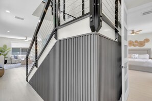 Un interior moderno con una escalera, una cama y un ventilador de techo.