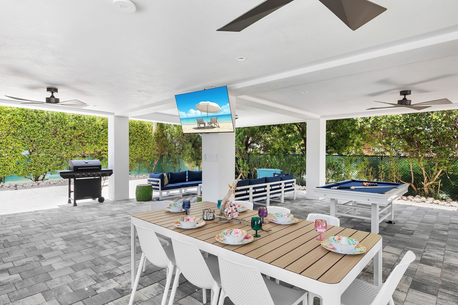 An outdoor patio with a pool table, a barbecue grill, and a seating area with a view of the sea.