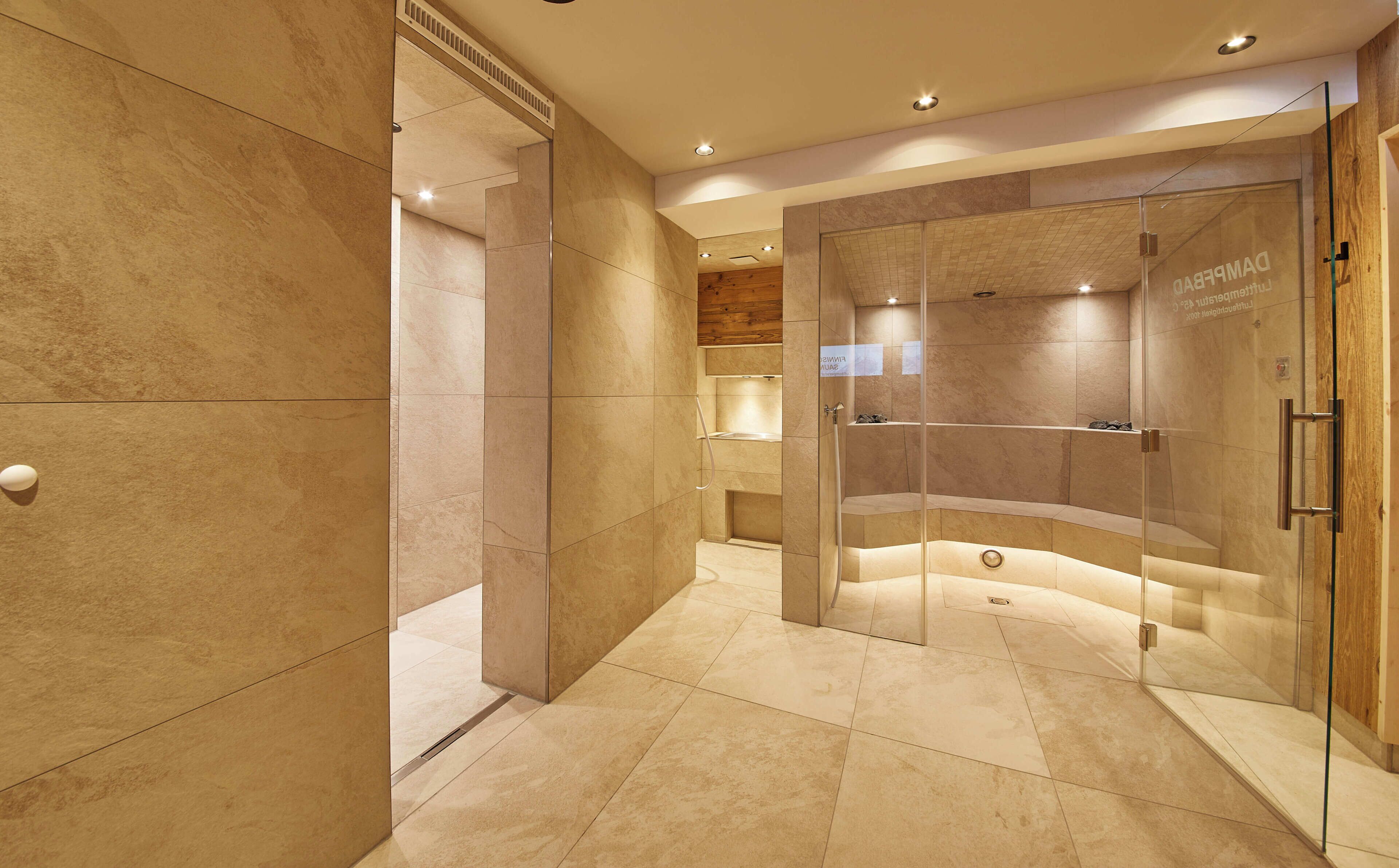 Un baño moderno con cabina de ducha de vidrio, suelo de mármol y techo de madera.