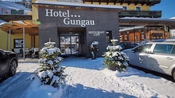 A hotel named 'Hotel Gungau' with a restaurant cafe sign, snow-covered ground, and a car parked in front.