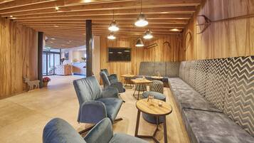 Un interior moderno con techo de madera, zona de estar y televisor.