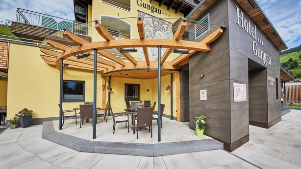 Un hotel con un área de estar cubierta al aire libre, un café restaurante y vistas a la montaña.