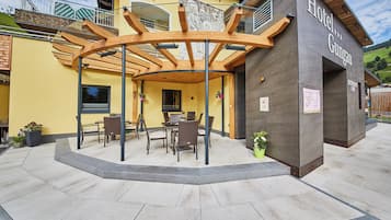 A hotel with a covered outdoor seating area, a restaurant cafe, and a mountain view.