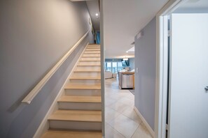 Eine Treppe führt zu einem Wohnbereich, im Hintergrund ist eine Küche zu sehen.