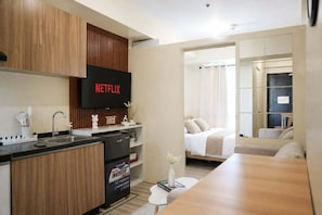 Ein modernes Hotelzimmer mit Küchenzeile, einem Bett, einem Badezimmer und einer Wohnbereicherung.