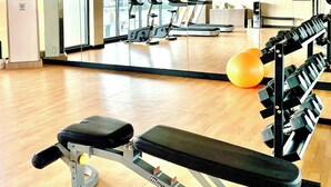 Ett gym med träningsredskap, ett löpband och en vägg med speglar.