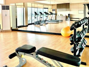 Ein Fitnessraum mit Trainingsgeräten, Laufband und Spiegelwand.