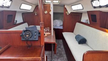 Een hutje met een bedieningspaneel, een bed met een opgerolde deken, en een kleine tafel met glazen.