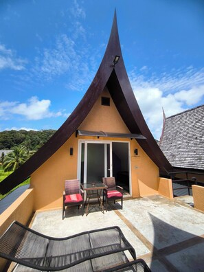 A modern building with a triangular roof, a sliding glass door, and outdoor seating.