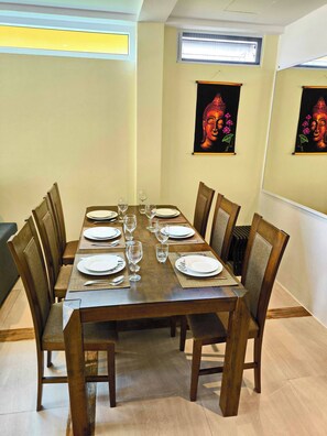 A dining area with a rectangular table set for six, surrounded by wooden chairs.