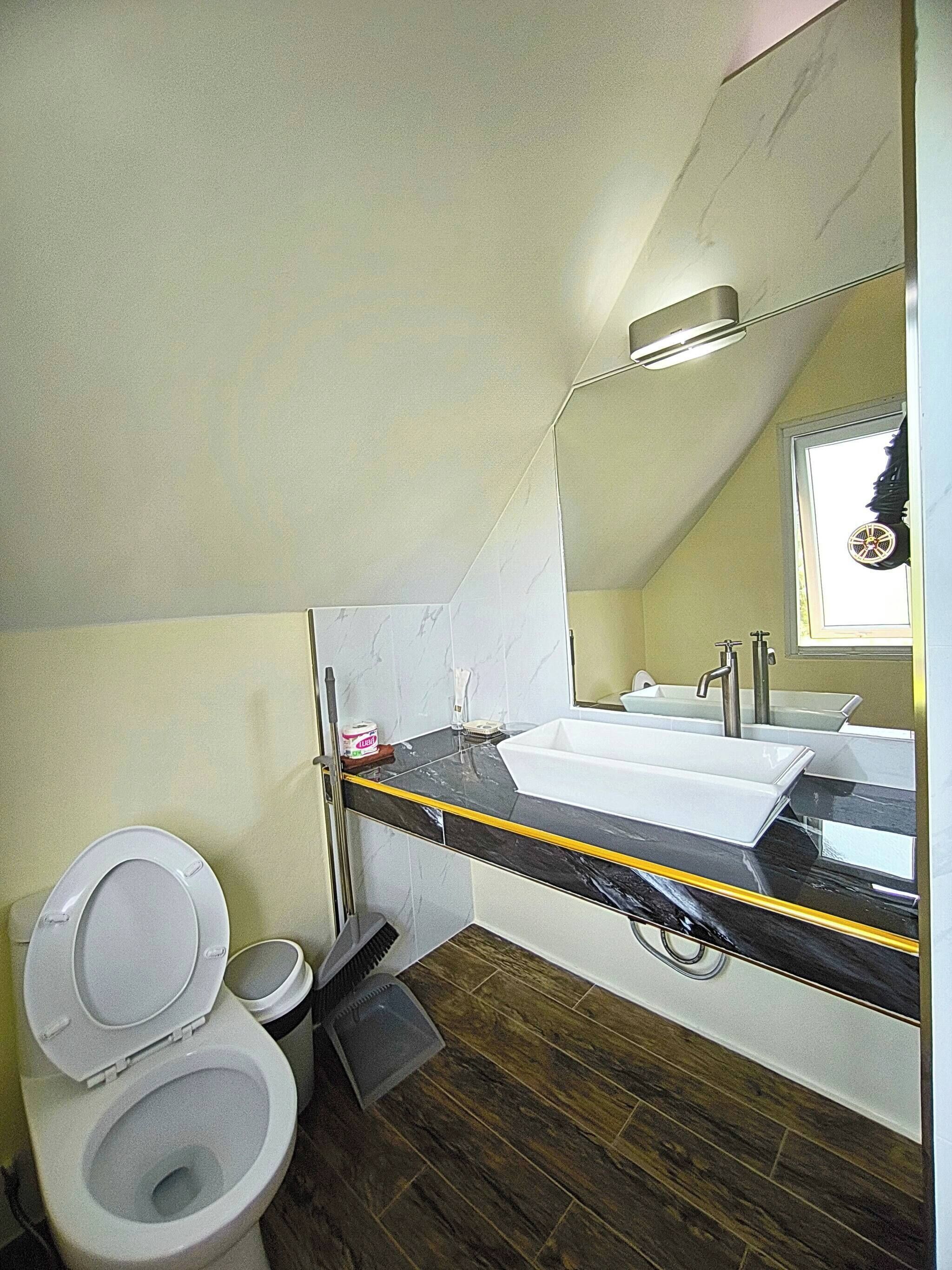 Et badeværelse med toilet, vask med spejl og et vindue.