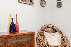 A wooden dresser with three colorful vases and a wicker chair with cushions. - [Portoseaview] Terrace+A/C (Portovenere)