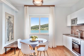 A modern kitchen with a dining area, a large window with a view, and a painting on the wall. - [Portoseaview] Terrace+A/C (Portovenere)