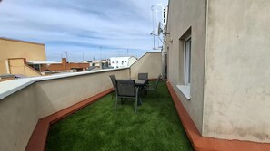 A rooftop terrace with artificial grass, a table, and chairs. - Ideal Accommodations in Madrid – Calle Cicerón with a Terrace (MADRID centro)