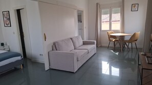 Ein modernes Wohnzimmer mit einer Couch, einem Esstisch mit Stühlen und einem Bett.