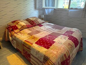 Ein Bett mit einer Steppdecke, ein Fenster und eine Wand mit Muster.