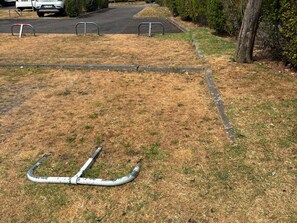 A grassy area with a metal structure, a paved path, and a parked car. - Charming apartment near the beach - 2 guests (Villers-sur-Mer)