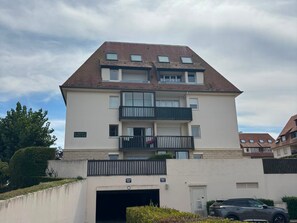 Ein mehrstöckiges Wohngebäude mit einer Garageneinfahrt, Balkonen und blauem Himmel.