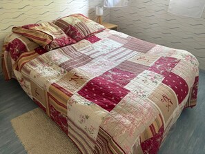 A bed with a quilt, a bedside table, and a lamp. - Charming apartment near the beach - 2 guests (Villers-sur-Mer)