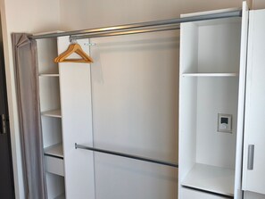 A walk-in closet with a hanging rod and open shelves.
