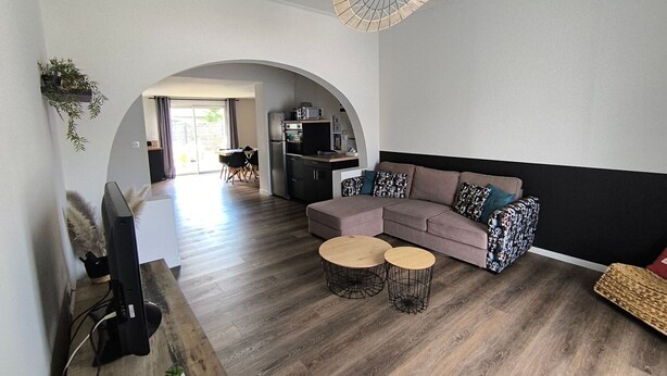 A modern living room with a sectional sofa, two round coffee tables, and a television.