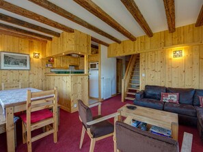 Ein gemütliches Blockhaus-Interieur mit Essbereich, einer Couch und einer Treppe, die zu einer oberen Ebene führt.
