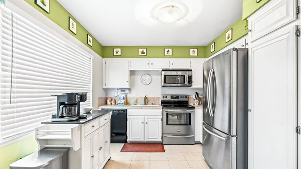 A compact kitchen with white cabinets, a stainless steel refrigerator, a microwave, and a dishwasher. - 25% Off Sept 10-13 Perfect 4 Families Pool, Tennis (Palm Springs)