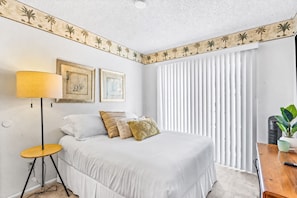 A bedroom with a bed, a bedside table, a lamp, a potted plant, and a window with blinds. - 25% Off Oct 22-25 Perfect 4 Families Pool, Tennis! (Palm Springs)
