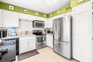 A modern kitchen with white cabinets, stainless steel appliances, and a green accent wall. - 25% Off Oct 22-25 Perfect 4 Families Pool, Tennis! (Palm Springs)