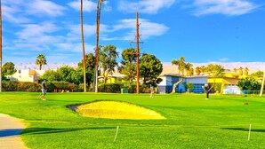 A golf course with a clear sky, palm trees, and buildings in the background. - 25% Off Sept 10-13 Perfect 4 Families Pool, Tennis (Palm Springs)
