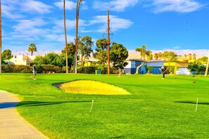 A golf course with a clear sky, palm trees, and buildings in the background. - 25% Off Sept 10-13 Perfect 4 Families Pool, Tennis (Palm Springs)