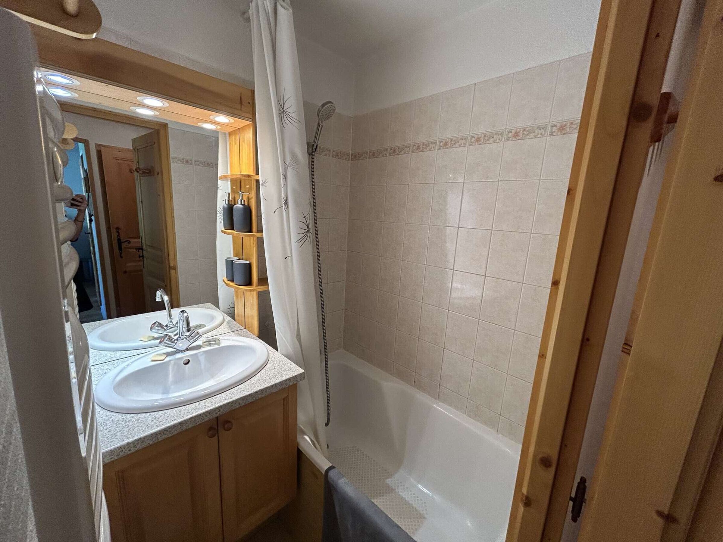 A bathroom with two sinks, a shower, and a wooden cabinet.