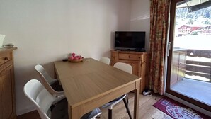 Un comedor con una mesa, sillas, un televisor y vistas a un paisaje nevado a través de una ventana.