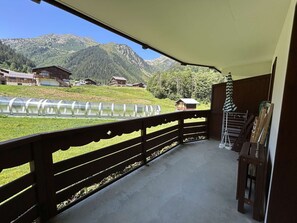 A balcony with a view of a mountain landscape, a wooden railing, and a small table with chairs. - Apartment with pets allowed - 4 guests at the foot of the slopes (Arêches-Beaufort)