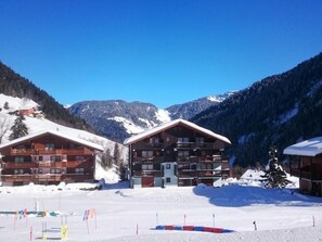 Eine Holzhütte mit Balkon, umgeben von schneebedeckten Bergen.