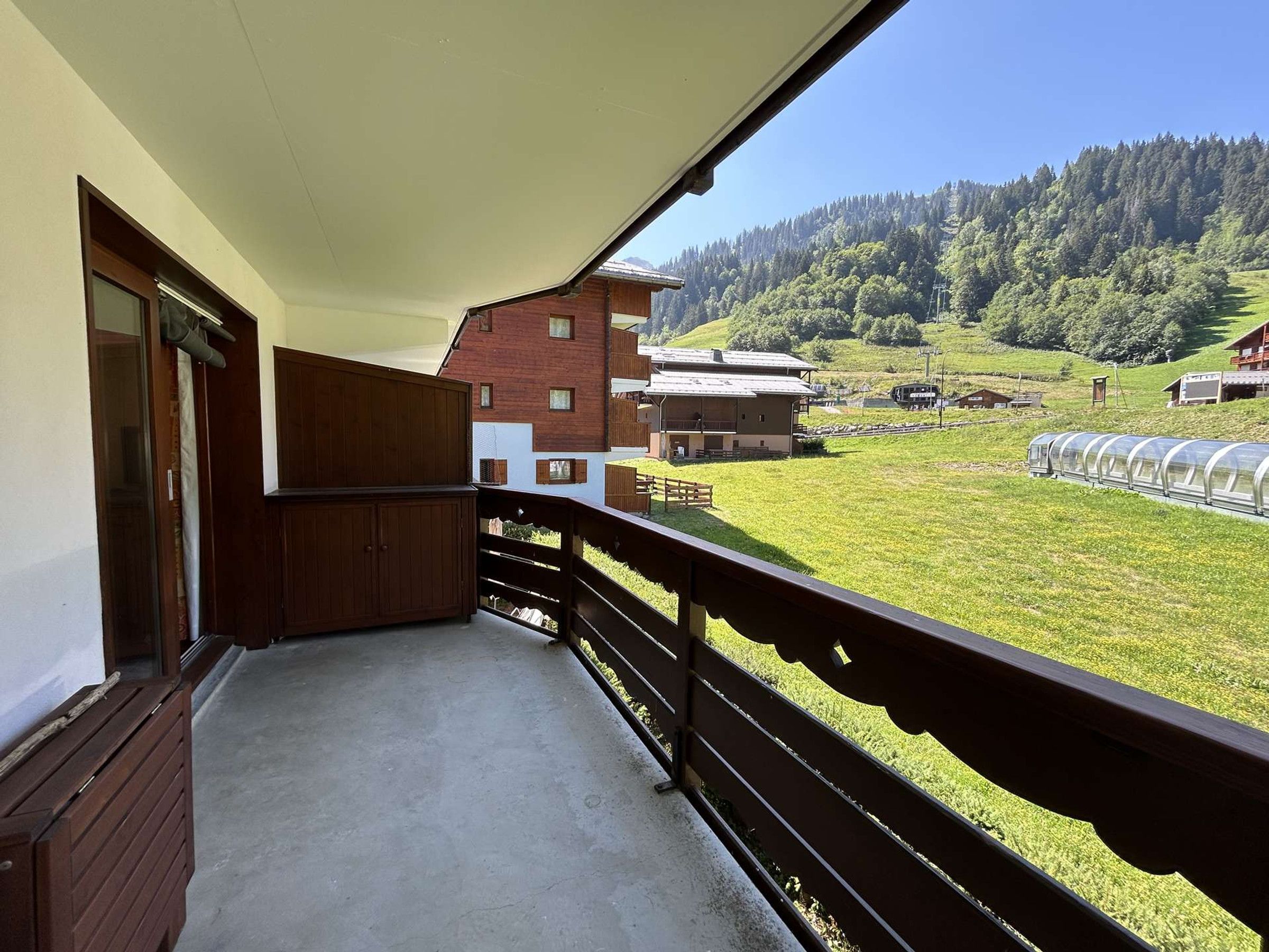 Ein Balkon mit Blick auf ein grünes Feld, einen Zug und Gebäude im Hintergrund.
