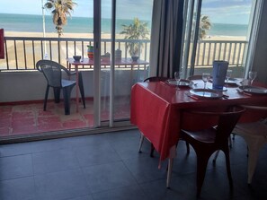 Ein Essbereich mit einem roten Tisch, Stühlen und Blick auf den Strand.
