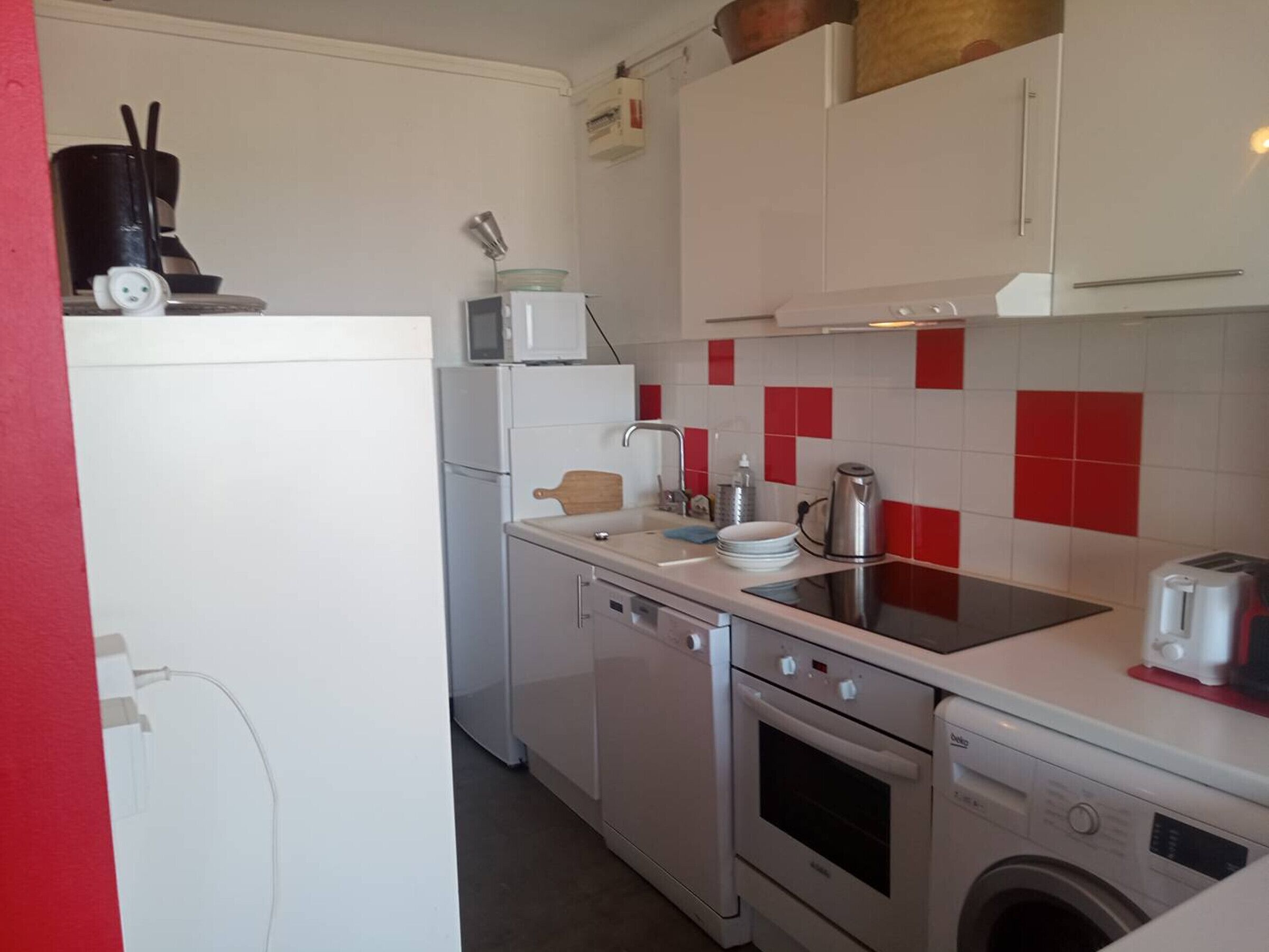 Una cucina compatta con forno a microonde, fornello, forno e lavatrice.